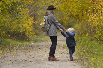 Mom and son are playing in the autumn forest.