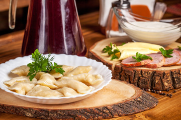 The concept of Ukrainian cuisine, vareniki with potatoes, with sour cream in a white plate on the table. breakfast in the restaurant. Copy space, selective focus