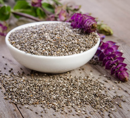 Chia seed healthy superfood in bowl with flower over wooden table