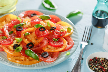 Freshness summer tomato salad carpaccio on blue plate on the table with fork.