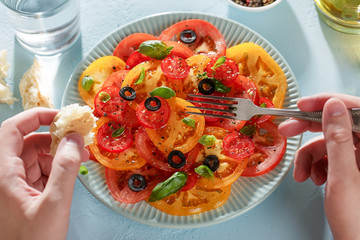 Man's hands eating homemade tomato carpaccio with bread and fork.