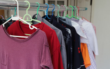 Closeup of purple T-shirt and others hanging on hangers for drying by sunlight. The simply lifestyle. 