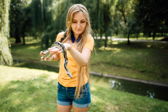 beautiful blonde girl is holding a snake in her hands. Contact the zoo.