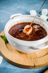 Chocolate fondue with marshmallow, winter party food, light blue background copy space