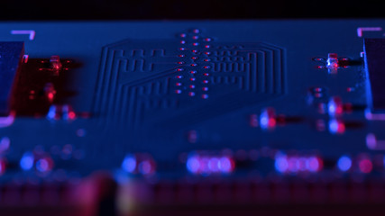 High tech electronic PCB close up in blue and red rays. Technology background.
