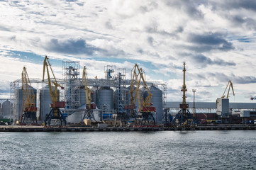 Industrial port with portal cranes and silos waiting for ships.