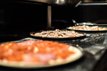 Close-up of three pizza in the making ready for oven