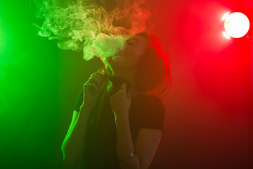 Young woman in neon light and smoke of e-cigarettes or vape