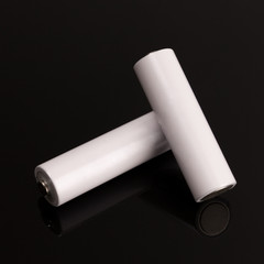Two white batteries on a glass table.