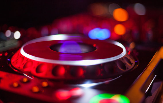 bokeh of DJ turntable and music deck illuminated at night with colourful lights lighting 