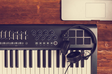 music production set midi piano keyboard retina laptop black dj headphones on wooden desk table. Top view filter