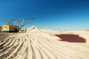 Quarries for the extraction of minerals. Dredging machine and a bright red lake. Ecological problems.
