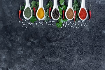 Crédence de cuisine Cuisine assortment of indian spices and herbs in ceramic spoon on black background, chili peppers and greens.  © tgordievskaya