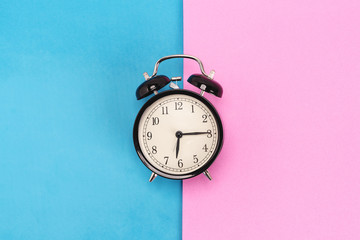 Vintage alarm clock on pink and blue background