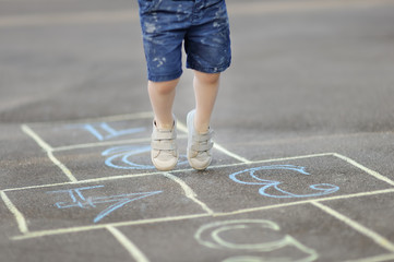 Closeup of little boy's legs and hopscotch drawn on asphalt