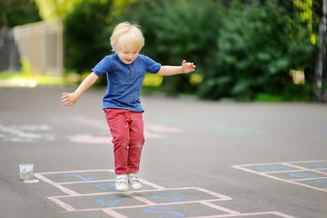 Child playing hopscotch on playground outdoors on a sunny day