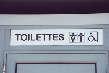 französische Toilettentür einer öffentlichen Toilette mit der Aufschrift "Toilettes" und Symbolen