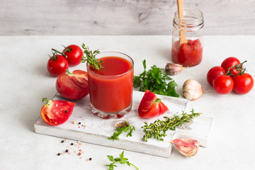 Cold summer soup gazpacho in glass with ingredients for preparation (fresh tomatoes, parsley, thyme, garlic, salt and pepper). Summer vegetarian food. 
