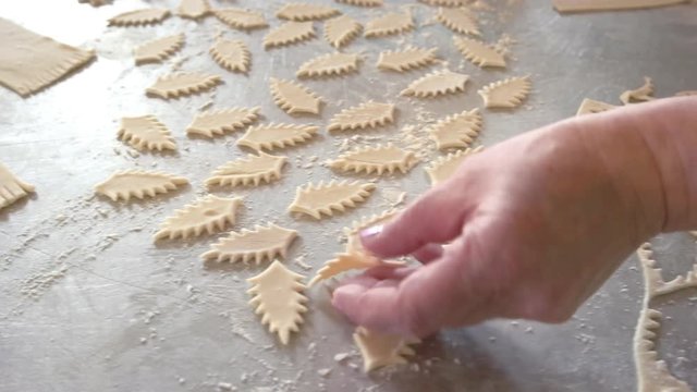 Baker cutting cookies from dough. Raw dough in a shape of leaves on table. Tips for making shaped cookies.
