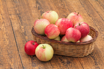 Red apples in wicker basket on wooden boards