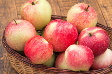 Red apples in wicker basket on wooden boards