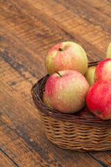 Red apples in wicker basket on wooden boards