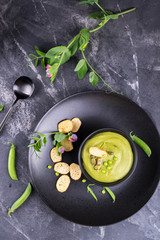 Light summer  delicious green peas cream soup served with pumpkin seeds,  croutons on dark background.flat lay.