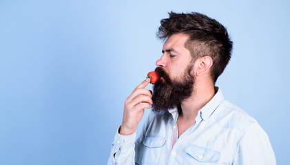 That is how tastes summer. Man handsome hipster with long beard eating strawberry. Hipster enjoy juicy ripe red strawberry. Man enjoy berry aroma. Berries season concept. Strawberry healthy snack