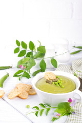 Green pea soup puree with croutons in black bowl.  On white background. Copy space