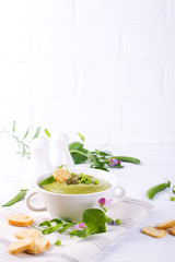 Light summer  delicious green peas cream soup served with pumpkin seeds,  croutons on white background.. Copy space