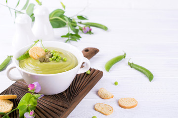 Light summer  delicious green peas cream soup served with pumpkin seeds,  croutons on white background.. Copy space