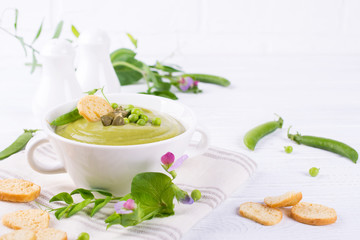 Light summer  delicious green peas cream soup served with pumpkin seeds,  croutons on white background.. Copy space