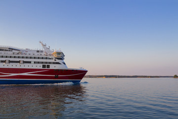 A tourist ferry sails in the waters of the Gulf of Finland near Helsinki on a summer evening. The concept of a beautiful sea trip with space for text.