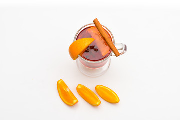 Mulled wine near slices of orange, top view. Glass with mulled wine or hot cider near juicy orange fruit on white background. Cocktail and bar concept. Drink or beverage with orange and cinnamon