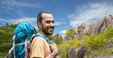 adventure, travel, tourism, hike and people concept - smiling man with backpack over background of seychelles island - obrazy, fototapety, plakaty
