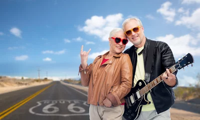 Poster rock music, old age and travel concept - happy senior couple with electric guitar over us route 66 background © Syda Productions