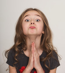 Little girl pleading with hands clasped together