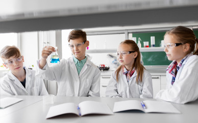 Fototapeta premium education, science and children concept - kids with test tubes studying chemistry at school laboratory