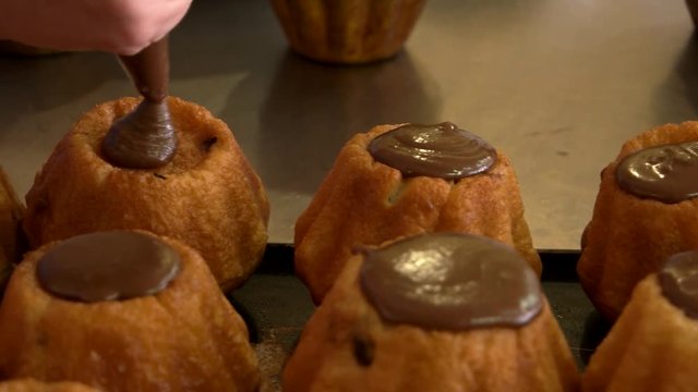 Close up chef decorating rum baba with cream. Confectioner filling cupcakes with chocolate icing using pastry bag. Confectionery business concept.