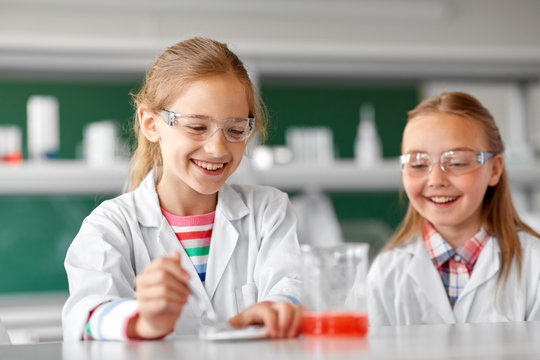 education, science, chemistry and children concept - kids or students making chemical experiment at school laboratory