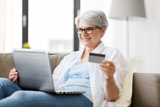 technology, online shopping and people concept - happy senior woman in glasses with laptop computer and credit or bank card at home