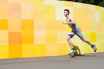 Young man running against bright wall