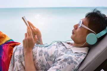 Asian man Freelance working and check email by mobile phone which on line working  in a vacation summer concept on the beach