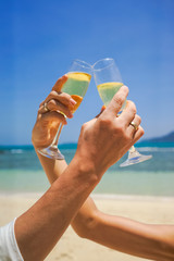 Hands of the bride and groom with glasses of champagne against the sky. Unification of two loving people, celebration and toast.