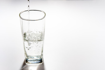 Pour drinking water into the tall glass.