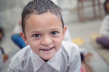 Smiling Indian/Asian Village School Boy Portrait sitting in his classroom.