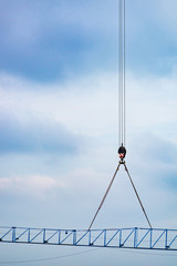 Setting up a blue tower crane in the construction site with a heavy mobile industrial yellow crane. Lifting the jib. Hook close-up.