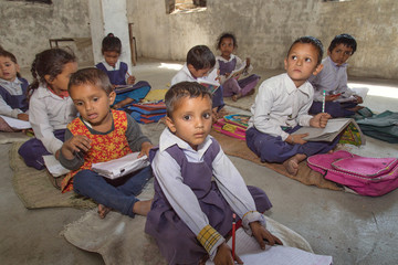 Indian Rural school kids learning from books in the classroom.