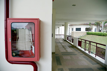 Fire extinguisher and fire hose reel in hotel corridor. Fire hoses rack for use.