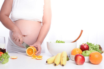 pregnant woman making salad on kitchen